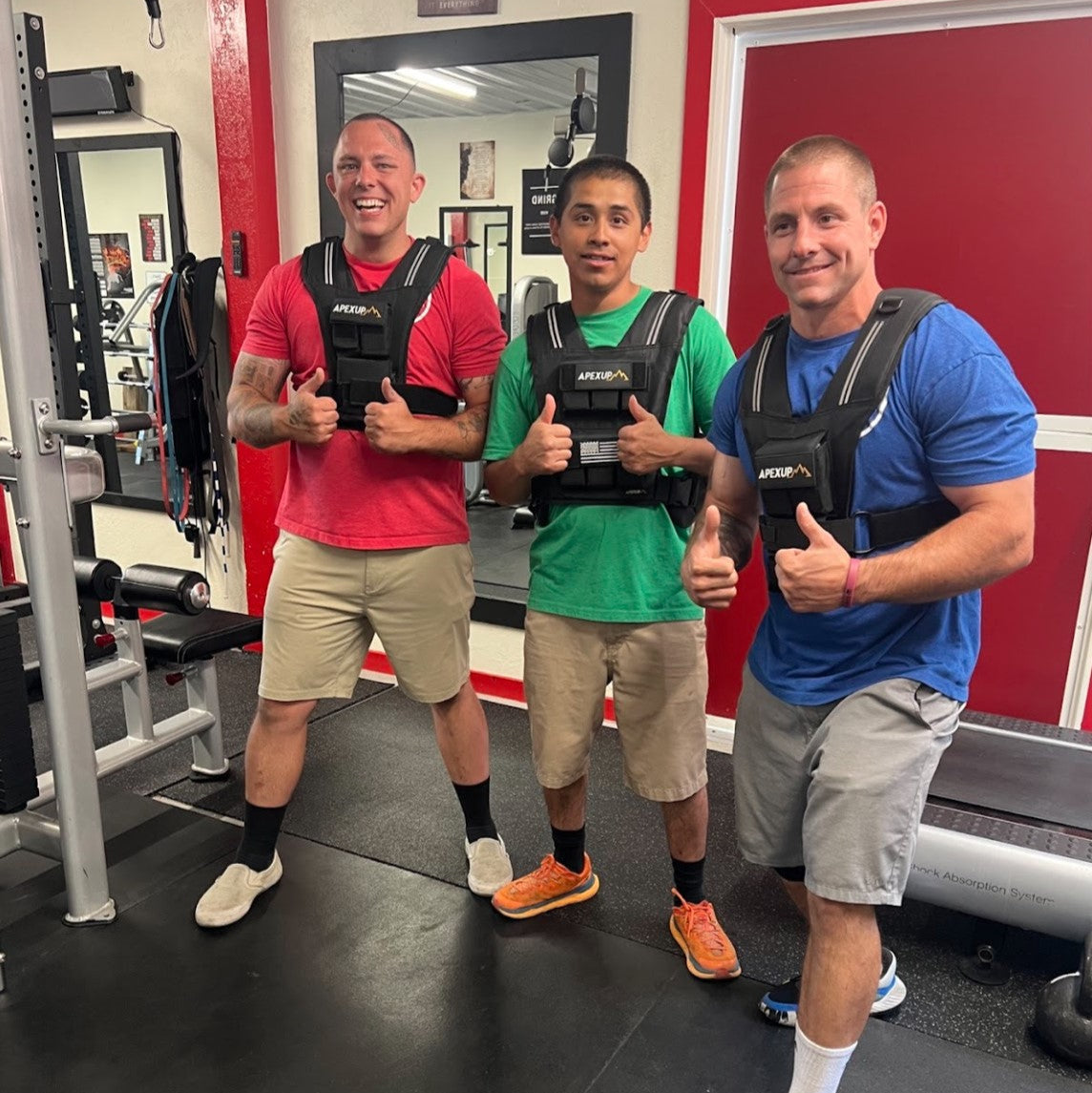 Three men wearing weighted vests in a gym setting