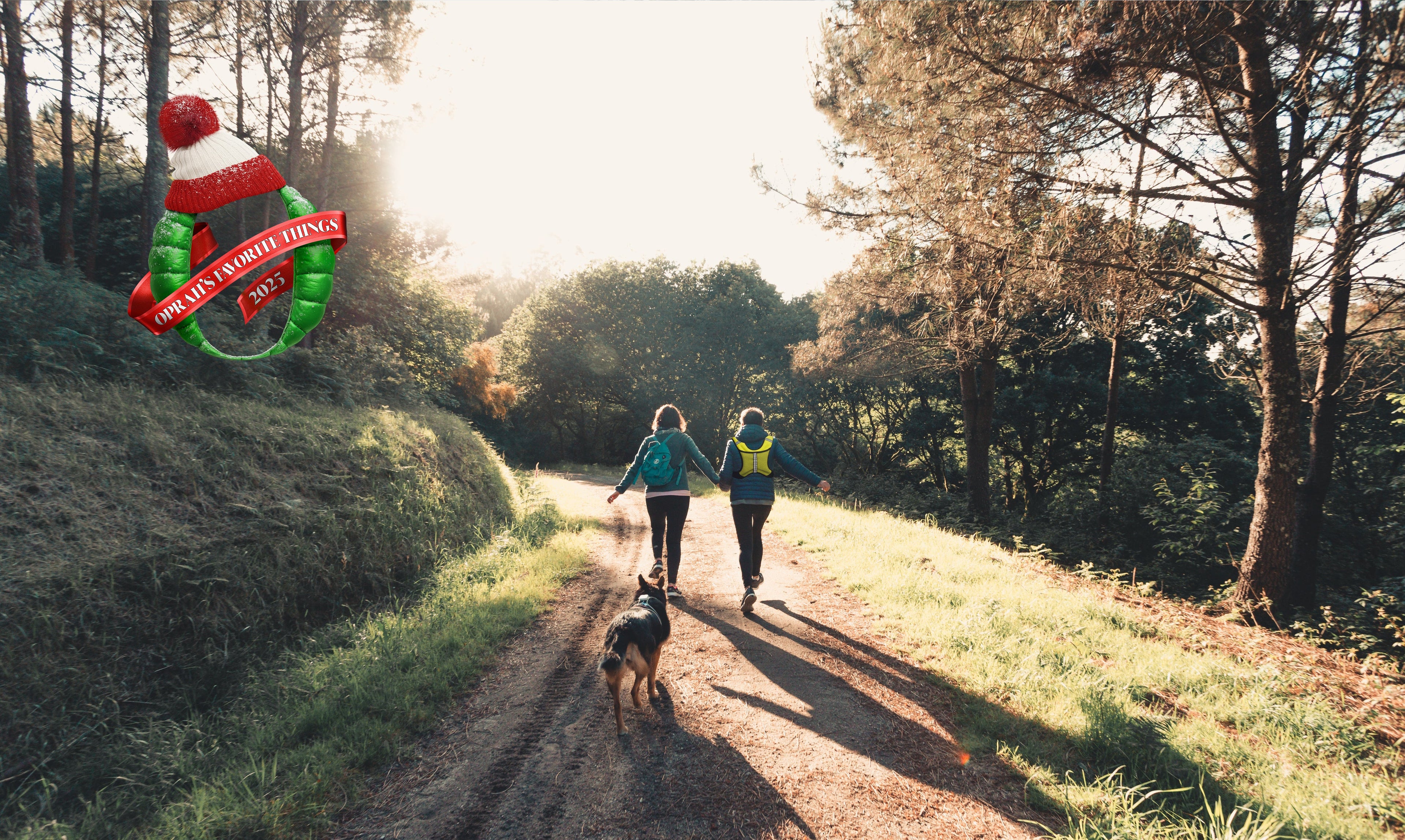 Two people walking a dog on a path in a forest with a Christmas-themed banner overlay.