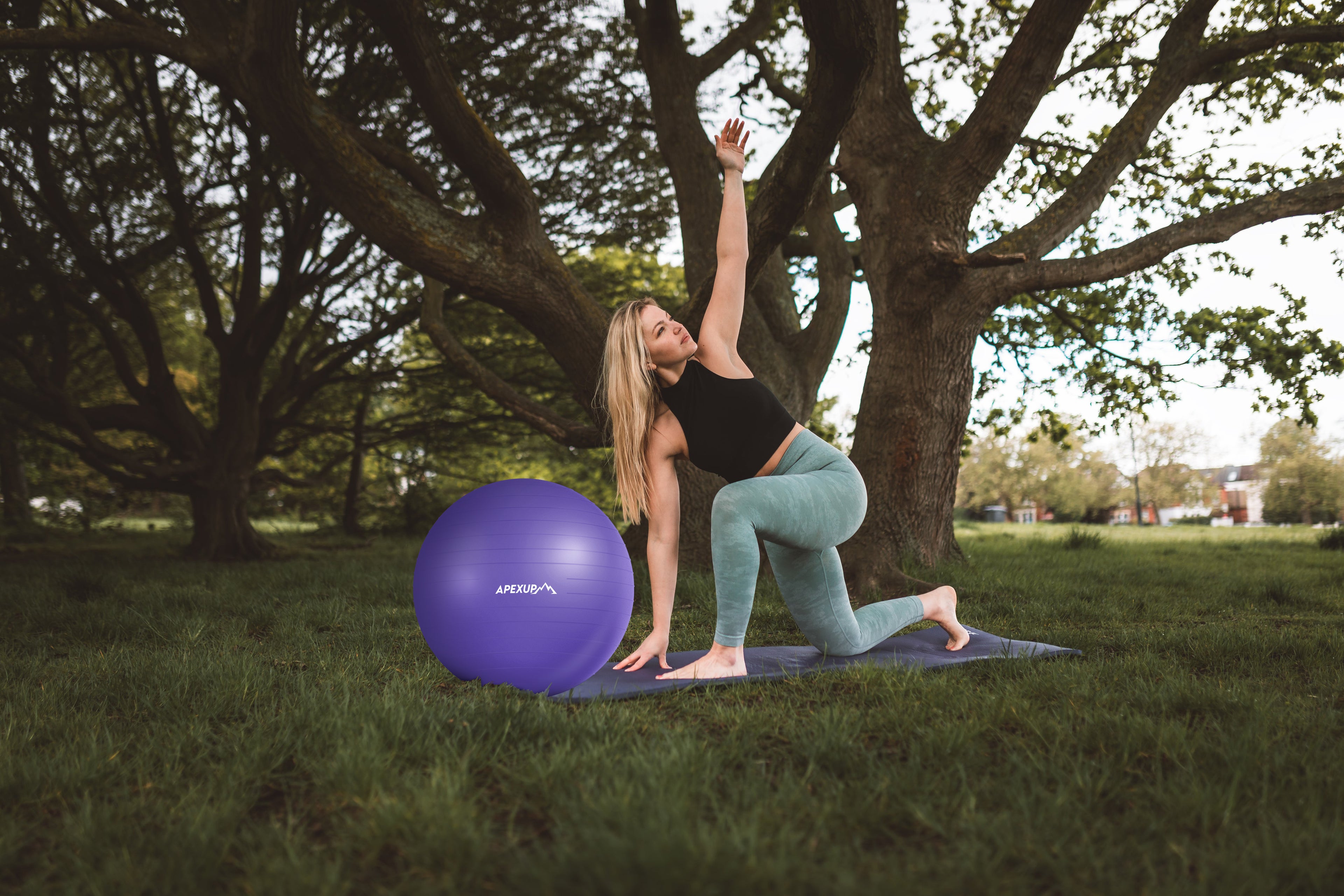 a woman is doing yoga in the park with apexup yoga ball